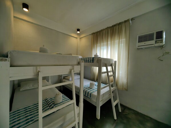 A bunk bed room with a single bed, a chair, a small table, and an air conditioning unit. - Alta Vista Ilocandia (Pagudpud)