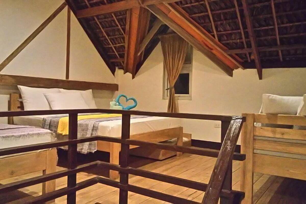 Une chambre à coucher rustique avec des poutres en bois, un lit en mezzanine et une petite fenêtre.
