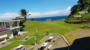 A hotel with a red roof, outdoor seating area, and a view of the ocean. - Alta Vista Ilocandia (Pagudpud)
