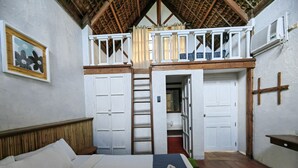 A bedroom with a bed, a wooden headboard, a balcony with a railing, and a view of the outside. - Alta Vista Ilocandia (Pagudpud)