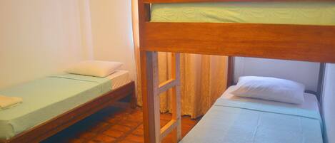 Una habitación con dos literas, una escalera de madera y suelo de baldosas.