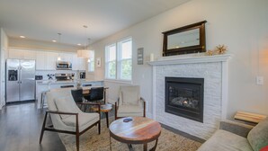 A spacious living room with a fireplace, a dining area, and a kitchen with modern appliances.