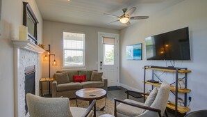 A living room with a fireplace, a ceiling fan, a television, and a coffee table.