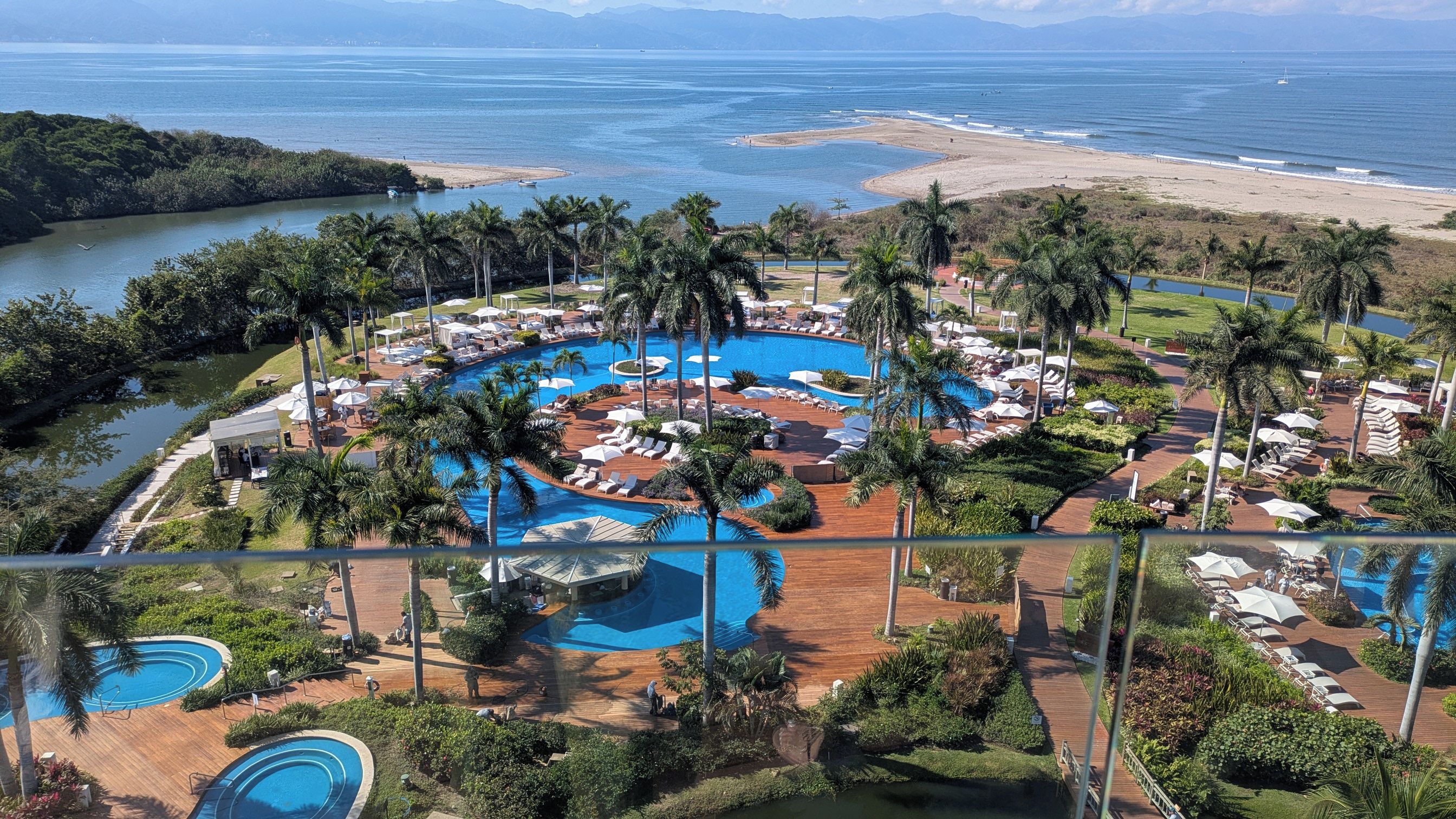 Ein Resort mit mehreren Schwimmbecken, Palmen und Blick auf den Strand.