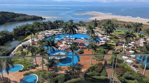 A resort with multiple swimming pools, palm trees, and a beach view.
