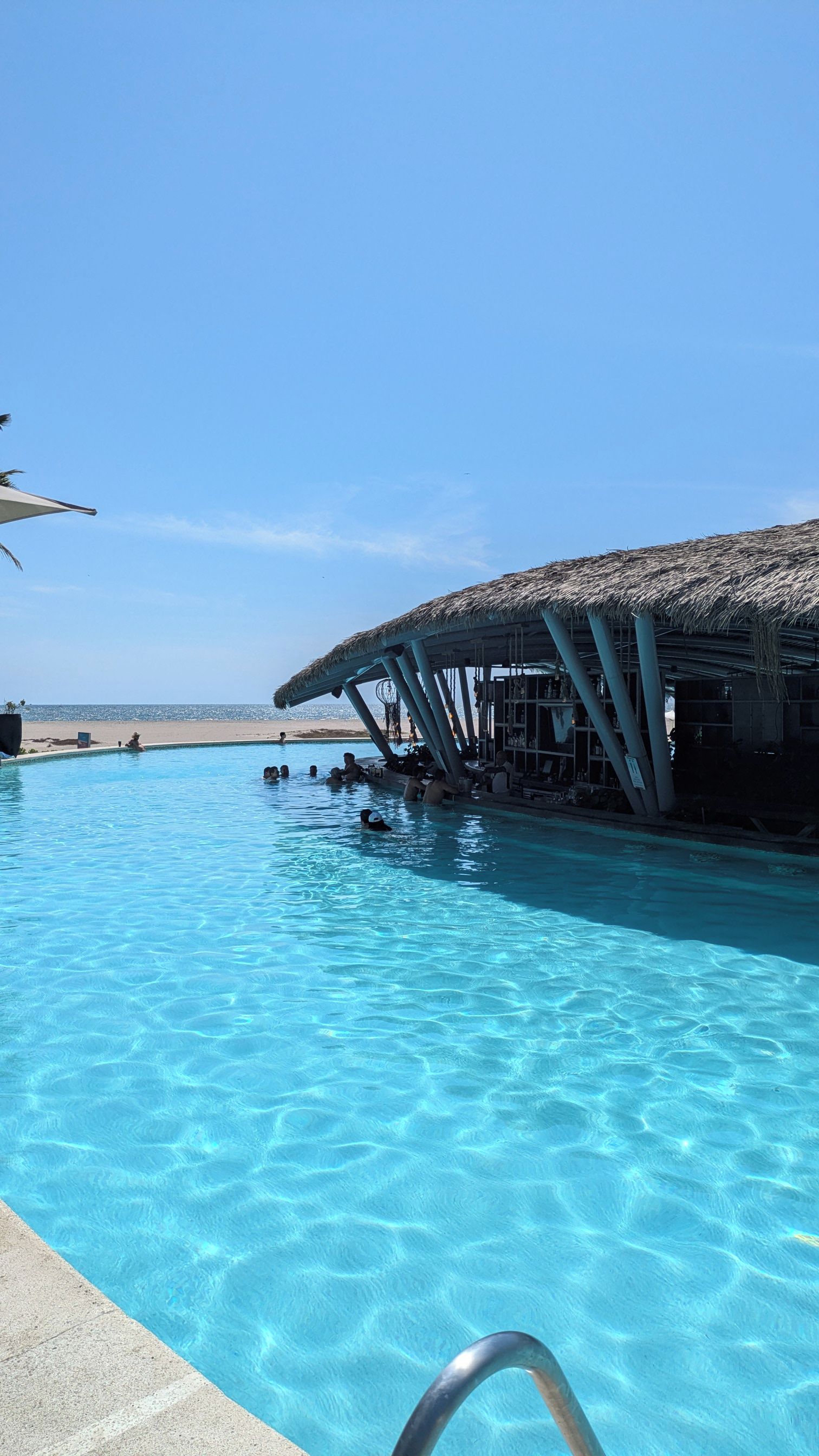 Une piscine d’eau cristalline, avec une structure à toit de chaume située juste à côté.