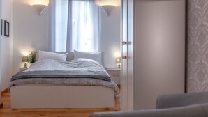 Um quarto com cama, mesas de cabeceira e uma janela com cortinas.