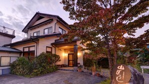 A traditional Japanese house with a tiled entrance, a wooden fence, and a stone with Japanese characters. - Yufuin Yamaboushi (Yufu)