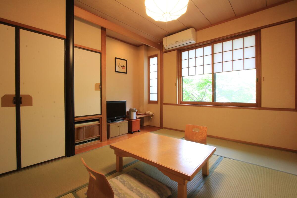 A traditional Japanese room with tatami flooring, a low table, and sliding doors.