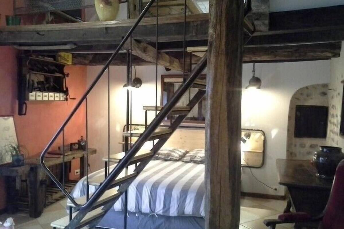Une pièce comprenant un lit, une chaise, une table et un escalier.