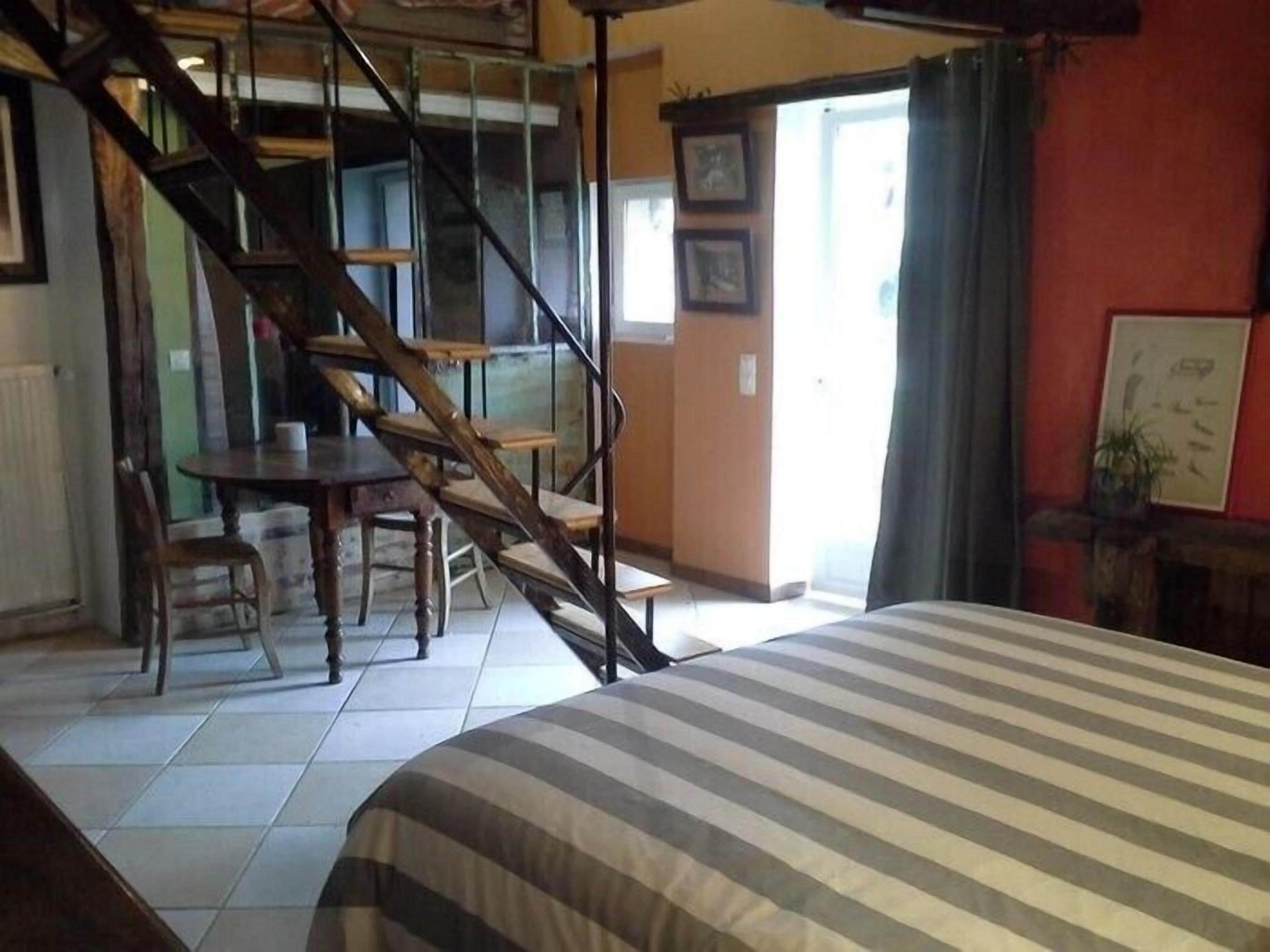 Une chambre à coucher avec un lit, un escalier, une table à manger et des chaises.