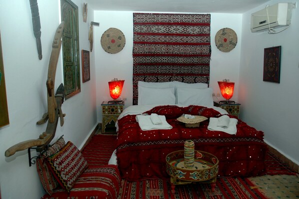 A traditional room with a bed, patterned textiles, and a decorative bowl.