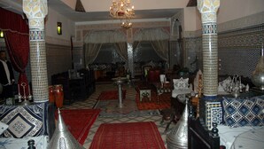 A traditional interior with ornate columns, a chandelier, and patterned rugs. - Riad Lahboul (Meknes)