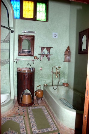 A bathroom with a wooden sink, a mirror, a bathtub, and a window with stained glass.