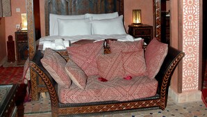 A four-poster bed with a patterned canopy, a nightstand with a lamp, and a decorative wall panel. - Riad Lahboul (Meknes)