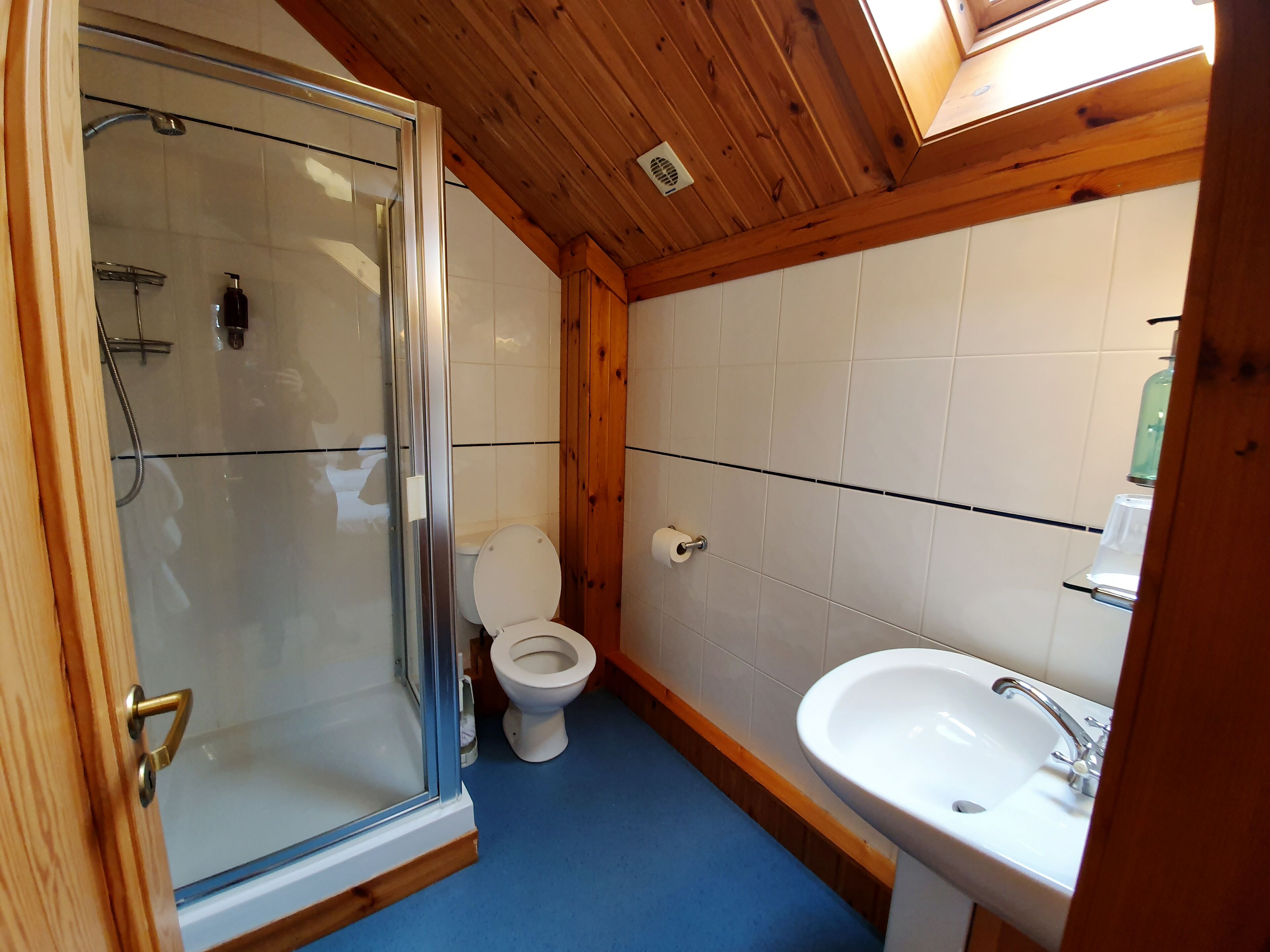 Une salle de bain avec une douche à parois de verre, des toilettes et un lavabo.