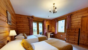 A wooden cabin bedroom with two beds, a desk, and a chandelier. - The Dorset Resort (Wareham)