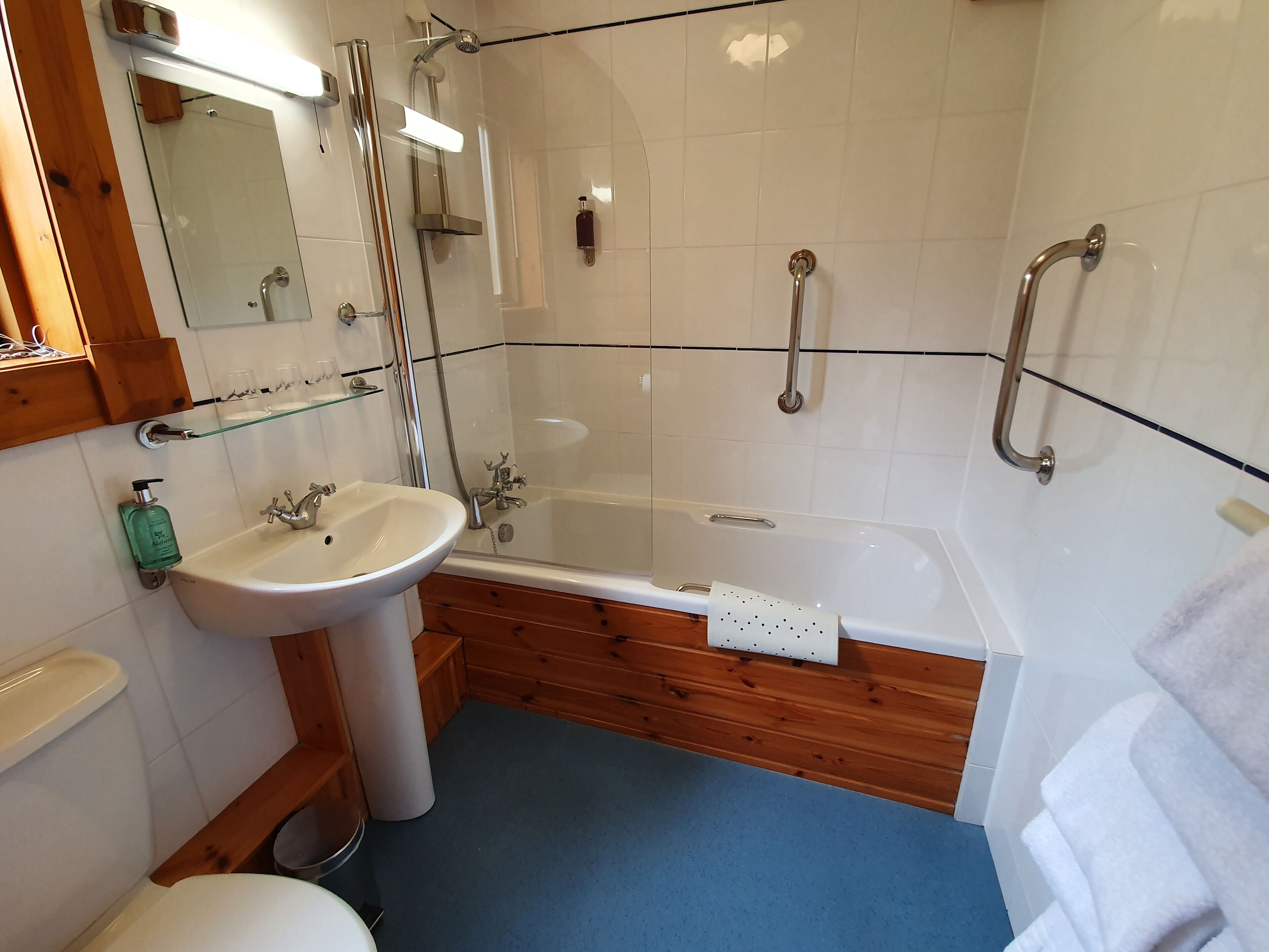 A bathroom with a white sink, wooden vanity, glass shower enclosure, and a bathtub.