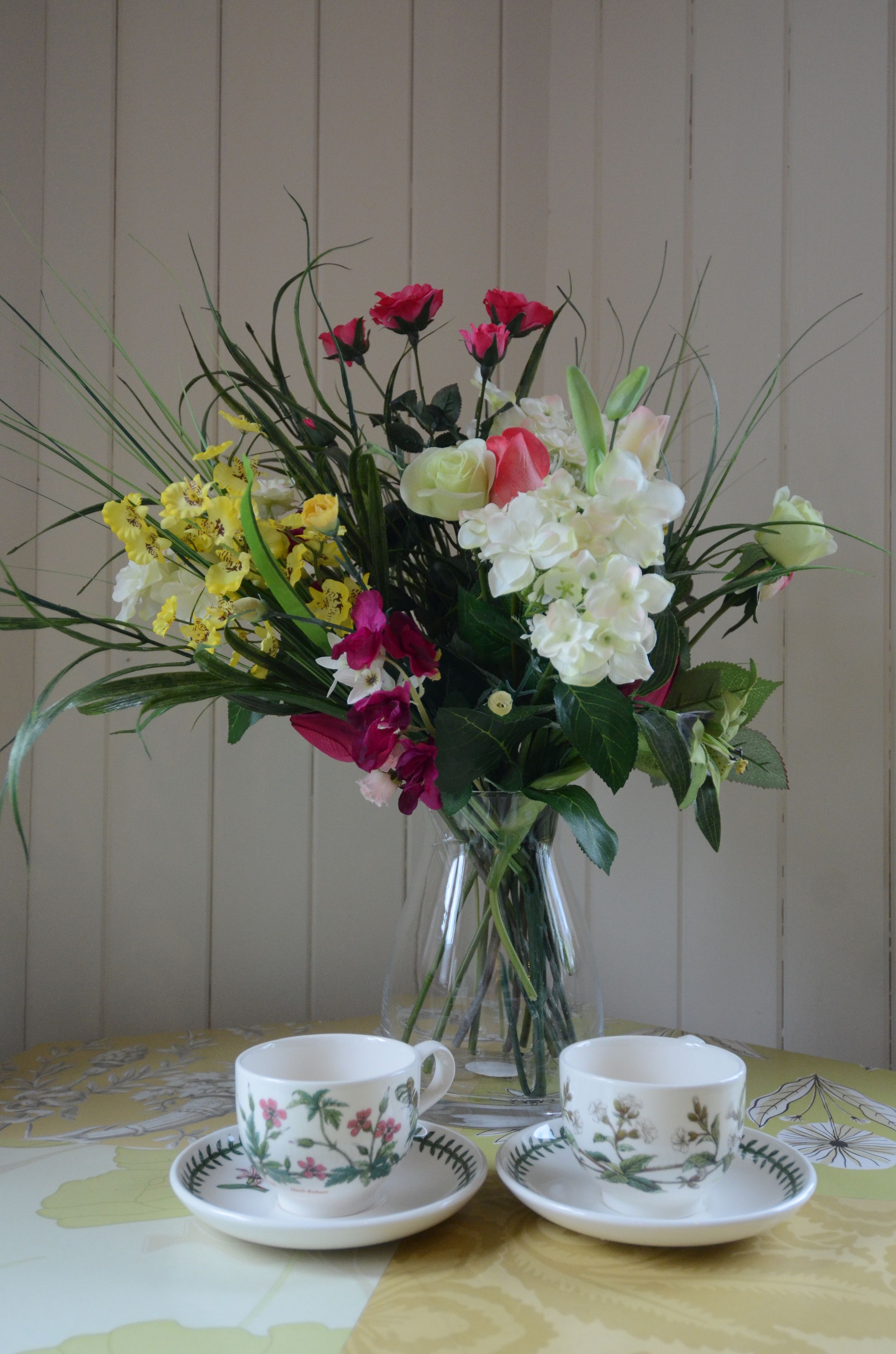 A table with a floral tablecloth and a vase of flowers.