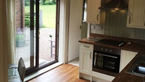 Una cucina con pavimento in legno, forno a incasso e una porta scorrevole in vetro che dà su uno spazio esterno.
