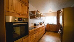 Een keuken met houten kastjes, roestvrijstalen apparatuur en een raam dat natuurlijk licht binnenlaat.