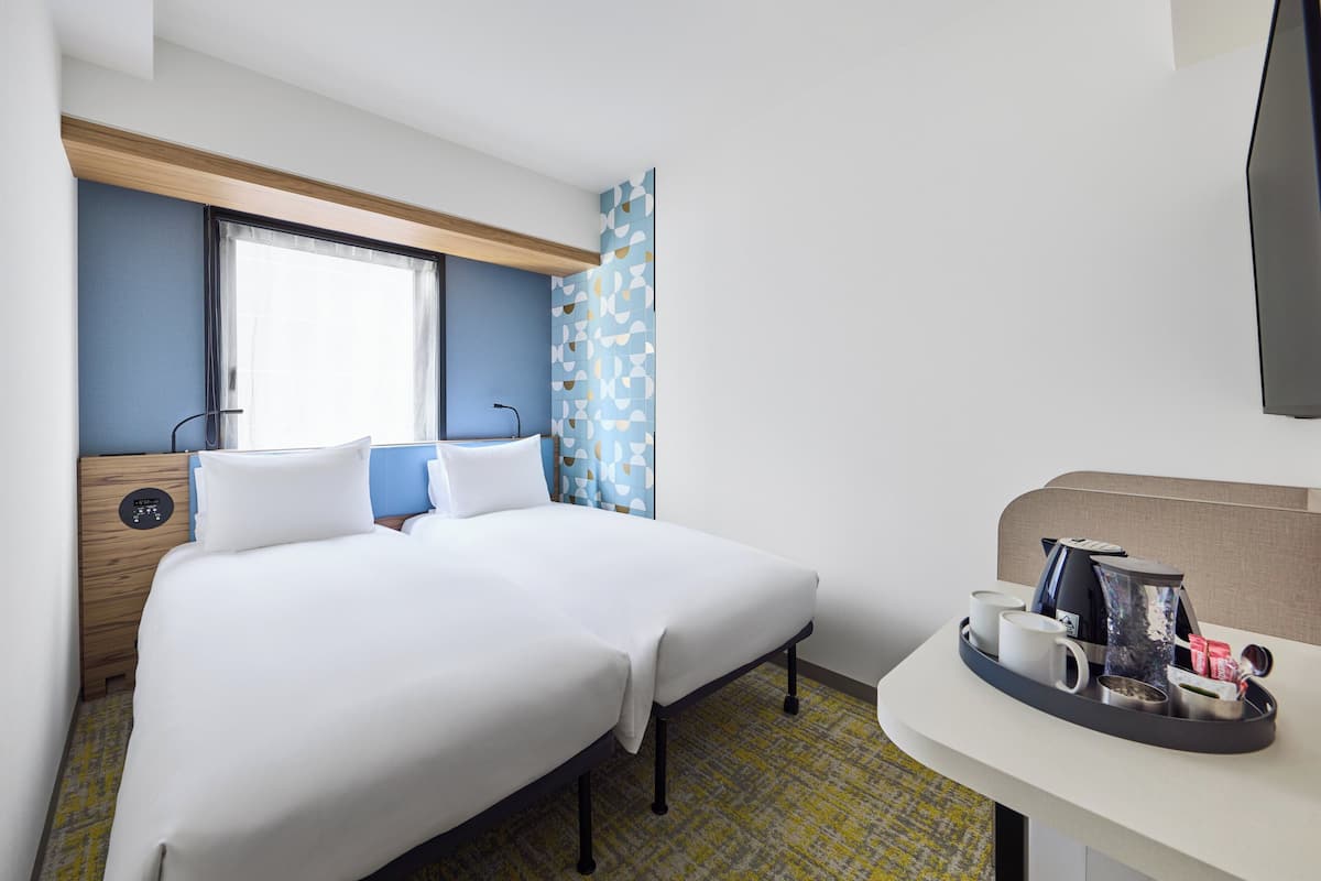 Quarto de hotel com uma cama, mesa de cabeceira e televisão.