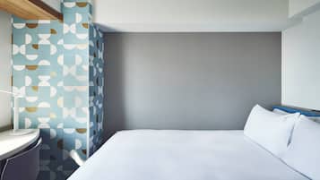A modern hotel room with a large bed, a bedside table, and a wall with a geometric tile pattern.