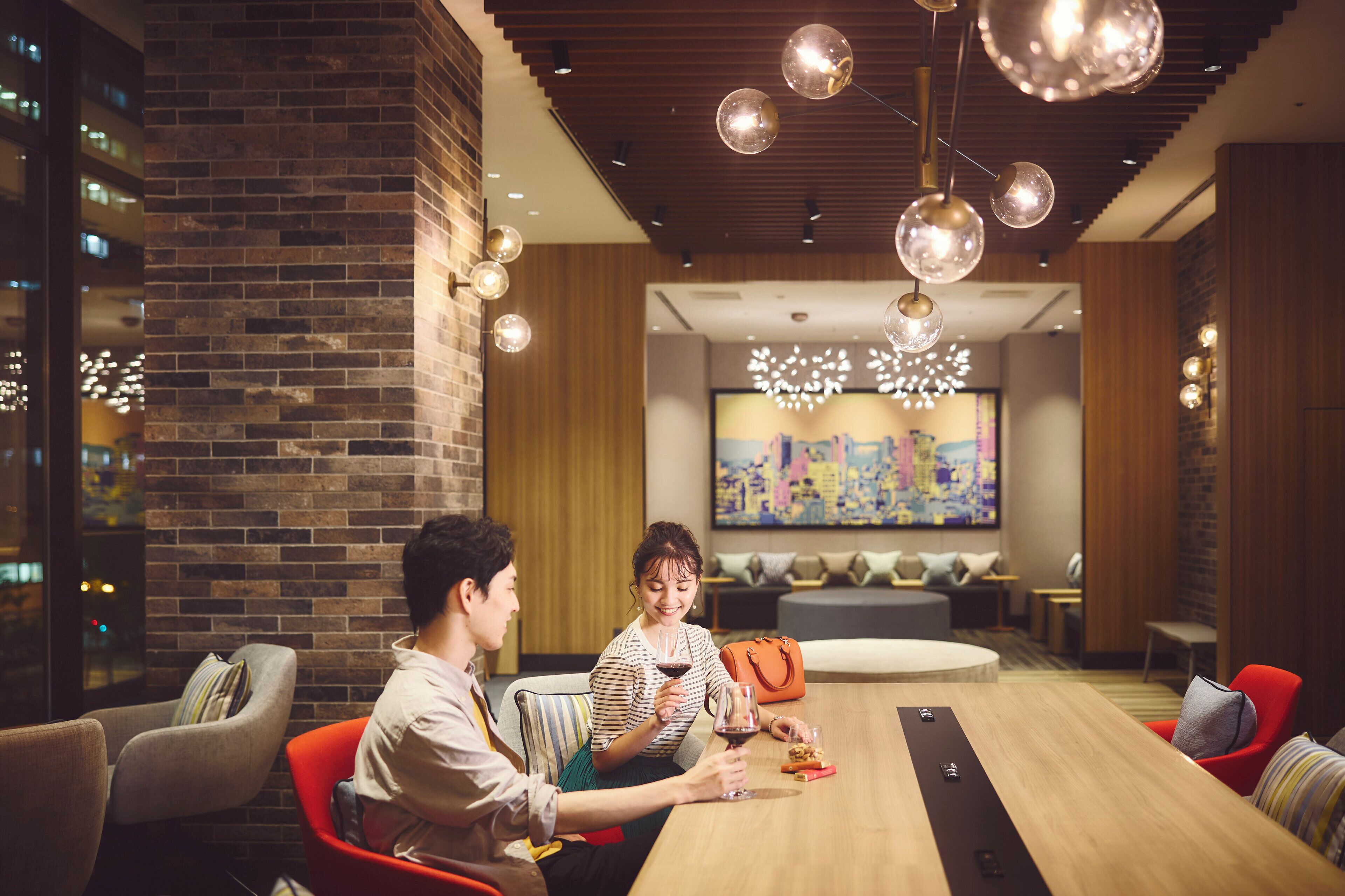A modern conference room with a wooden table, comfortable seating, and a cityscape painting on the wall.