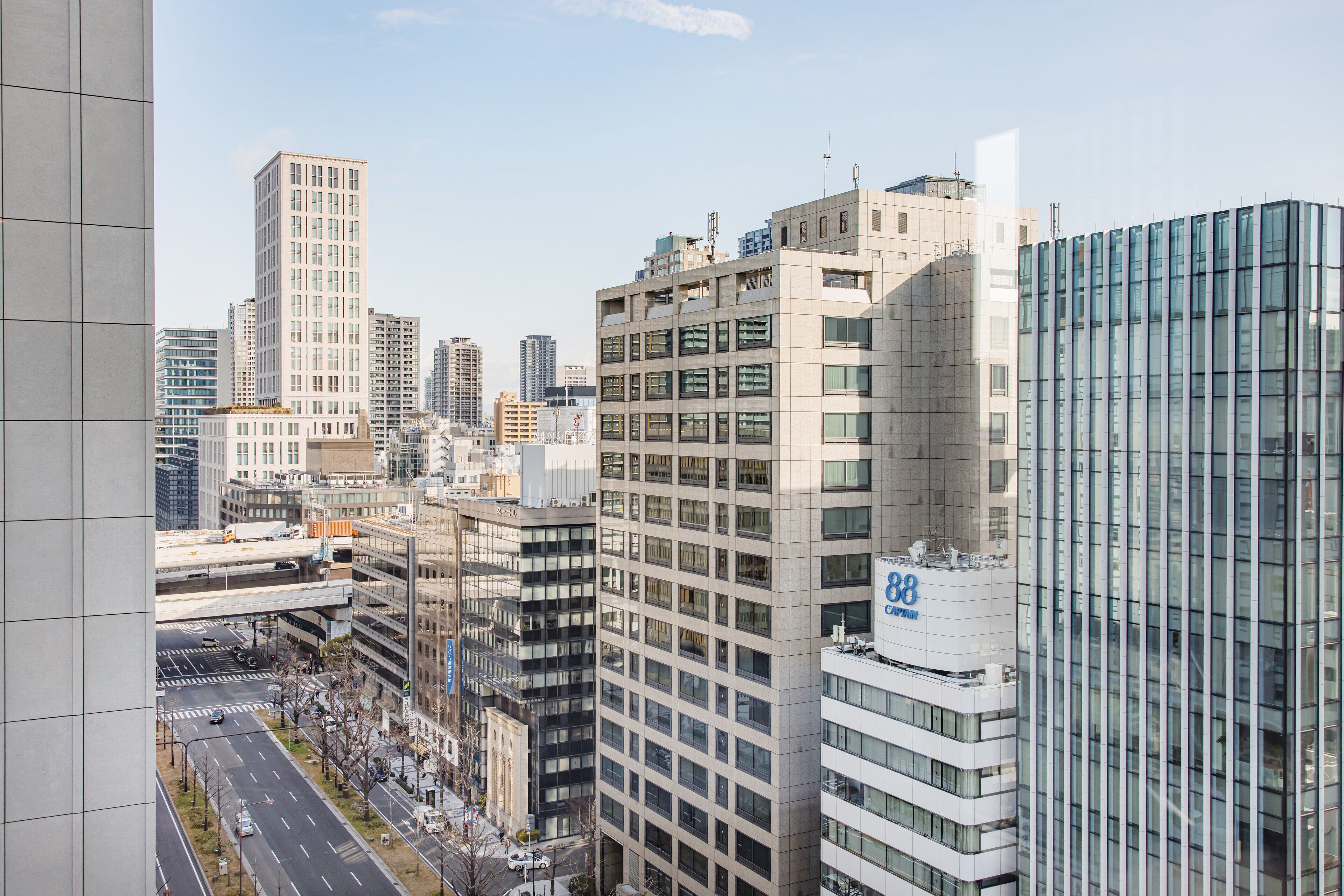 Un paisaje urbano con edificios modernos, incluyendo un edificio destacado con '88' y 'CA', que sugiere un hotel o edificio corporativo.