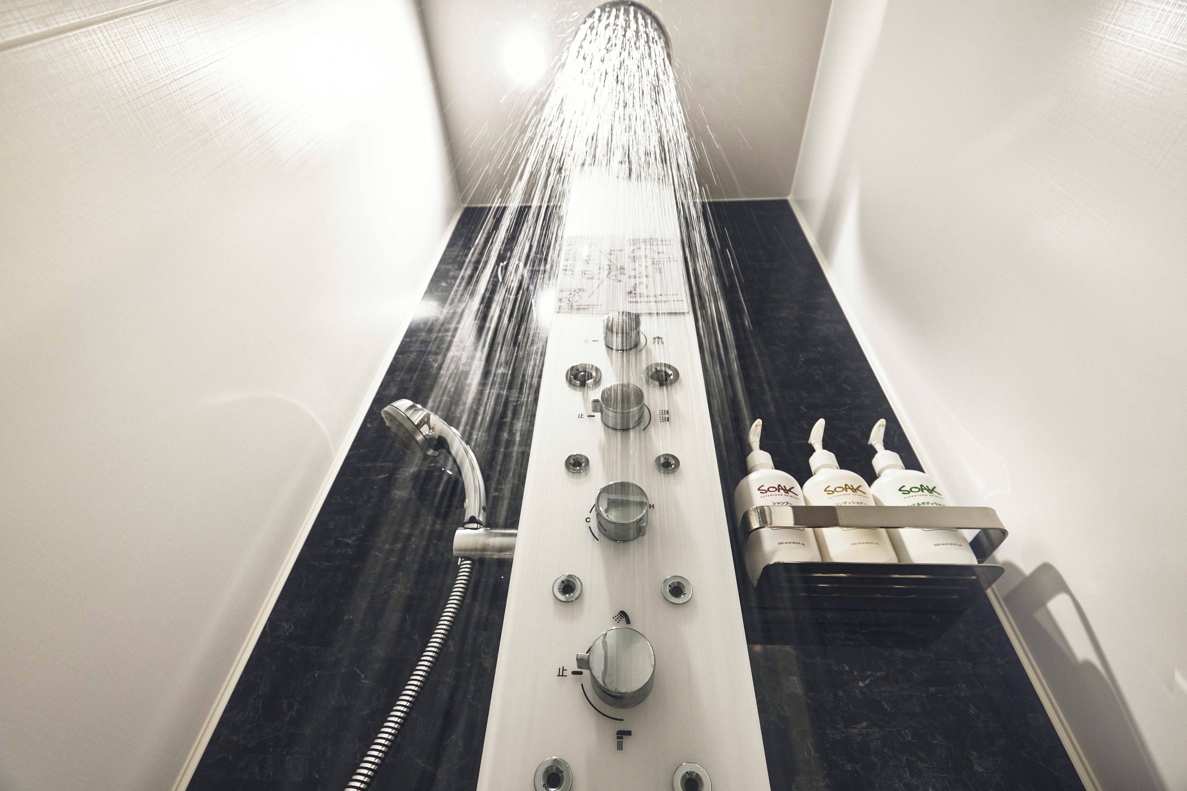 A shower with multiple water jets, a handheld showerhead, and a soap dispenser.