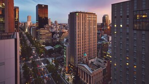 Un paisaje urbano con edificios altos, incluyendo un edificio prominente y alto con una torre de reloj y un edificio más pequeño con una cúpula.