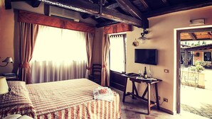 Una habitación de hotel con cama, escritorio con silla, televisión y ventana con cortinas.