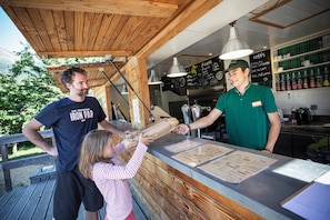 Une terrasse en bois avec un comptoir, des panneaux affichant le menu et une vue sur l’extérieur.