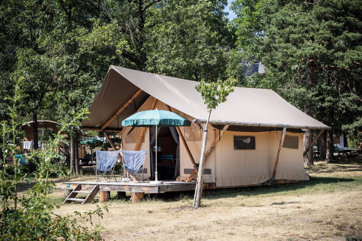 A tent with a covered porch, a ladder, and a table with chairs.