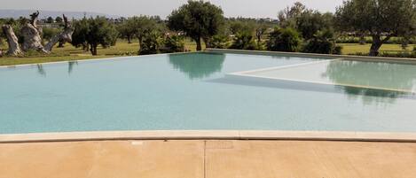 Una silla hamaca con vistas a una piscina, árboles y un cielo despejado.
