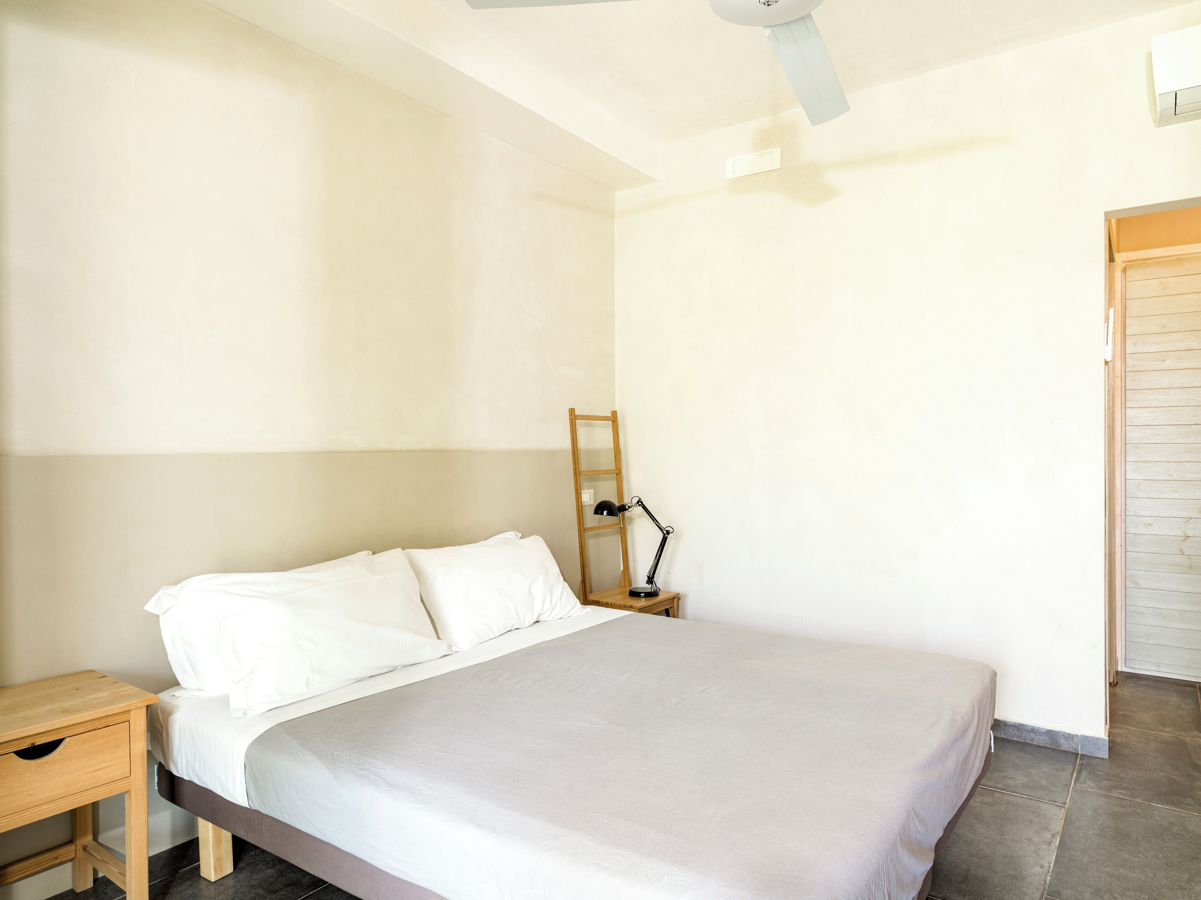 Un dormitorio con cama, mesita de noche, espejo y ventilador de techo.
