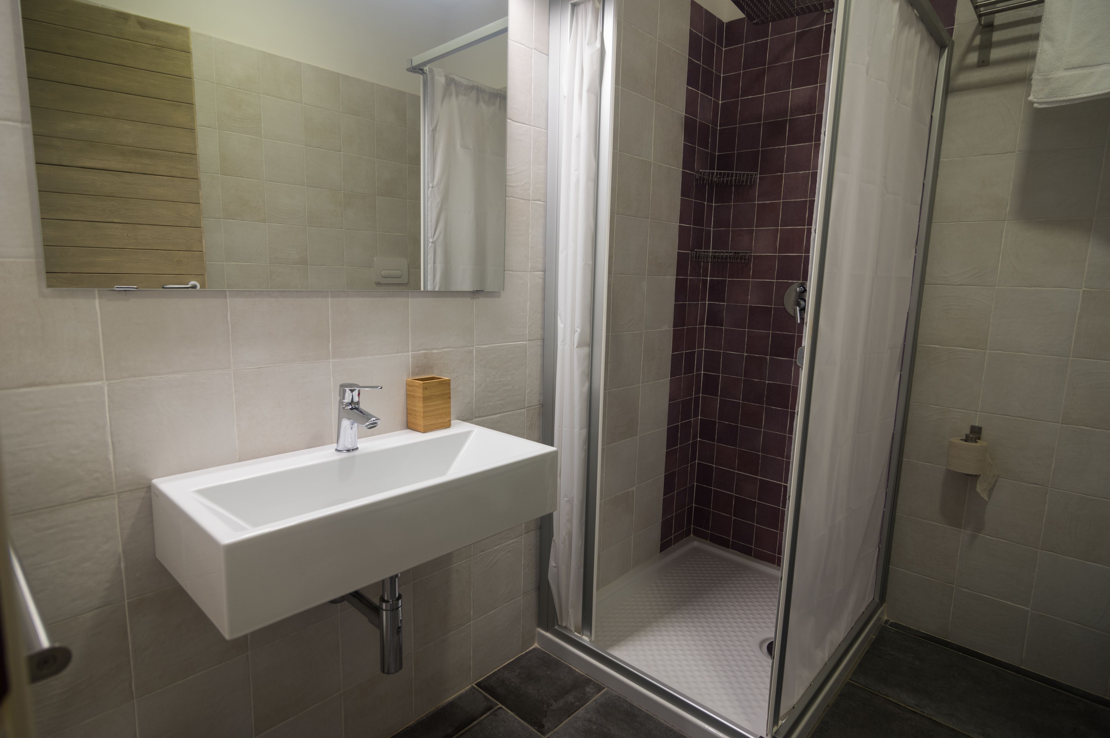 A bathroom with a white sink, a mirror, and a shower area with a glass door.