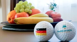 A table with a plate of fruit and two golf balls with a German flag design.