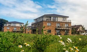 A multi-story residential building with balconies and a garden in the foreground. - Appartments an der Golfanlage (Rostock)