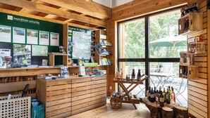 A wooden interior with a reception desk, informational posters, and a wine display. - Huttopia Font Romeu (Font-Romeu-Odeillo-Via)