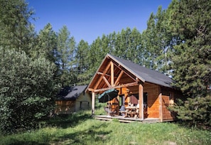 A wooden cabin with a porch, surrounded by trees. - Huttopia Font Romeu (Font-Romeu-Odeillo-Via)