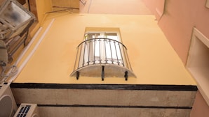 A narrow corridor with a window at the end, a radiator, and a wall with a black baseboard. - B&B Empedocle (Porto Empedocle)