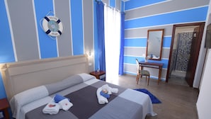 A hotel room with a bed, a desk, a chair, a mirror, and a life preserver on the wall. - B&B Empedocle (Porto Empedocle)