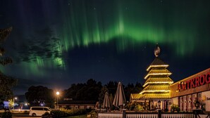 En byggnad med ett tak i pagodstil, en parkeringsplats och en skylt med texten ”JAMTKROOG”.