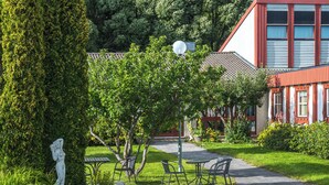 En trädgårdsdel med en staty, en lusthus och en byggnad med röda detaljer.