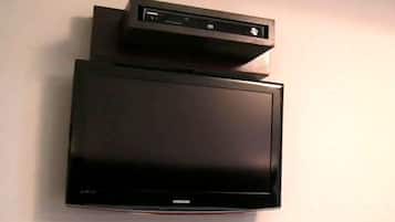 Un televisor de pantalla plana montado en la pared y un reproductor multimedia sobre un muro sencillo.