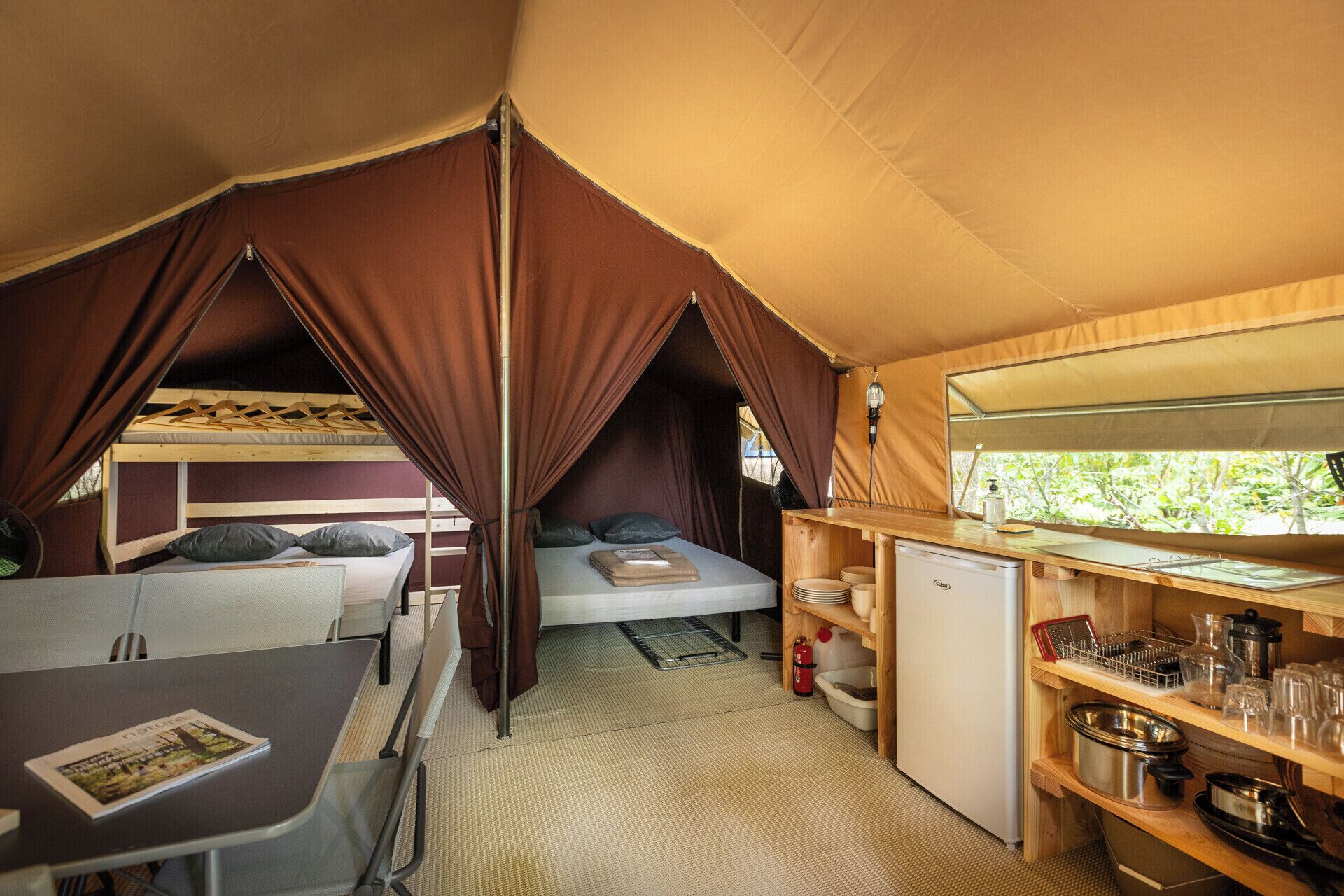 Eine Zelthütte mit Etagenbett, einer kleinen Küchenzeile und einem Essbereich.