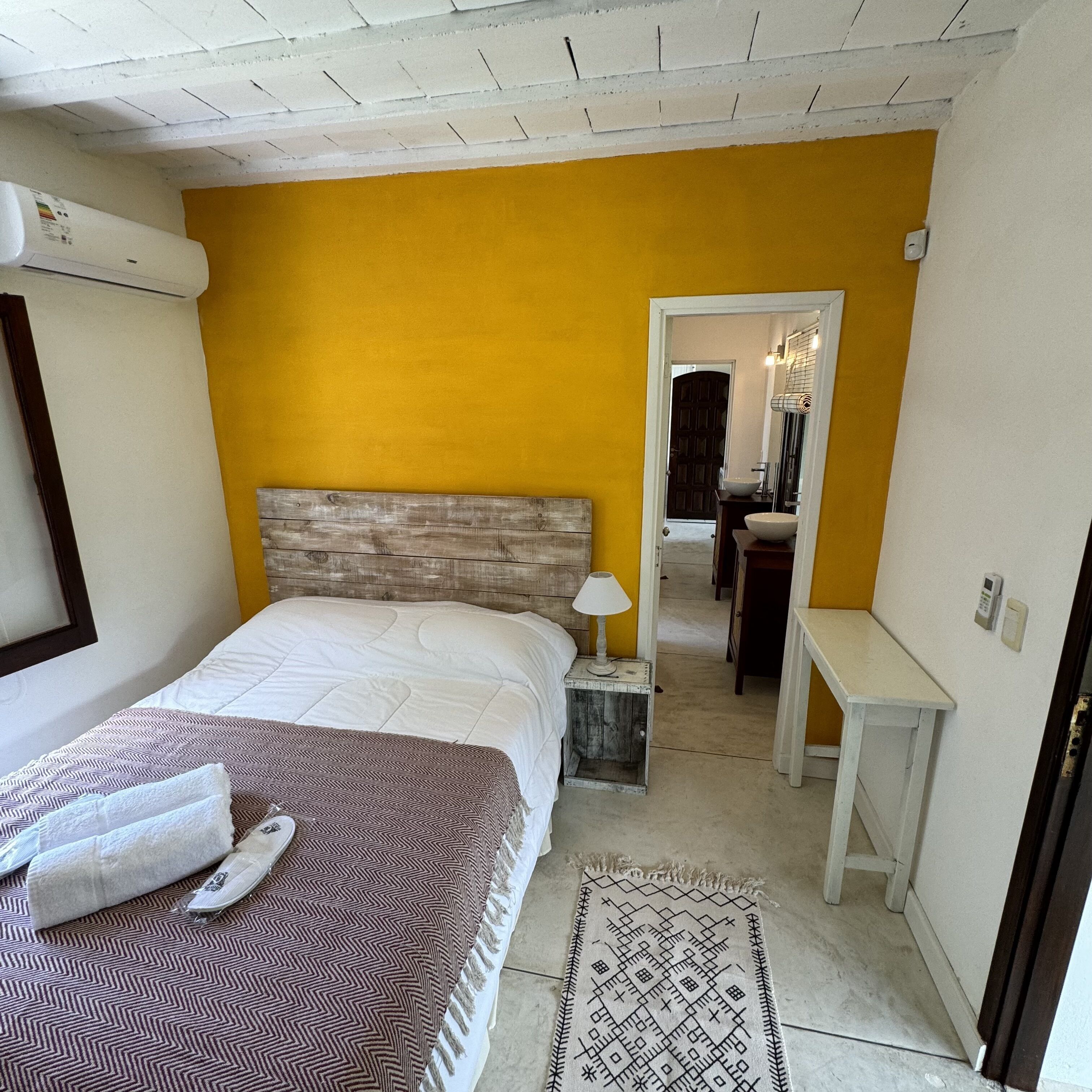 A bedroom with a bed, bedside table, lamp, and a rug.