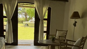 Una habitación con cama, una mesa y sillas, y vistas a un coche y vegetación afuera.