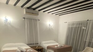 Habitación de hotel con dos camas, una zona de estar con una silla, una mesita y una alfombra grande.